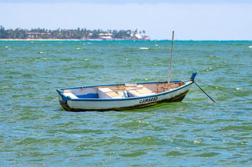 a small boat sitting in the middle of the water at Village Porto Feliz Itacimirim in Camaçari
