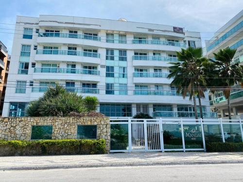 um edifício branco com um portão em frente em MANDAI Apartamento Cabo Frio em Cabo Frio