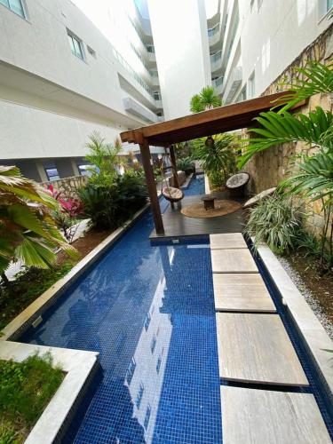 a swimming pool in a building with a table and a blue at MANDAI Apartamento Cabo Frio in Cabo Frio