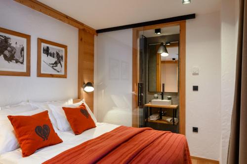a bedroom with a bed with orange pillows and a bathroom at Vila Pavlina in Kranjska Gora