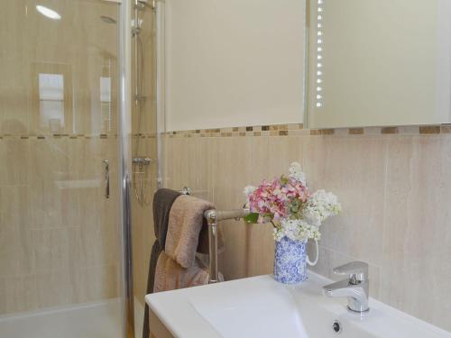 a bathroom with a sink with a vase of flowers on it at Woodlands Dairy Cottage in Billingshurst
