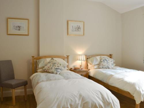 a bedroom with two beds and a chair and a lamp at Woodlands Dairy Cottage in Billingshurst