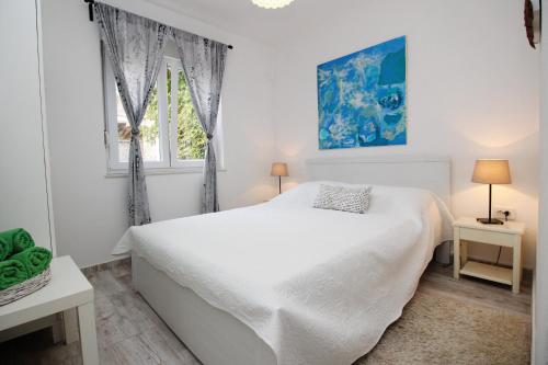 a white bedroom with a white bed and a window at Apartments Rozanda in Baška