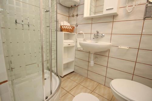 een badkamer met een toilet, een wastafel en een douche bij Apartments Rozanda in Baška