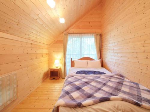 a bedroom with a bed in a wooden cabin at HARUNA CABIN 森の中のログハウス 、広々ウッドデッキでBBQ、公園散策、北軽井沢観光 in Azumaiokozan