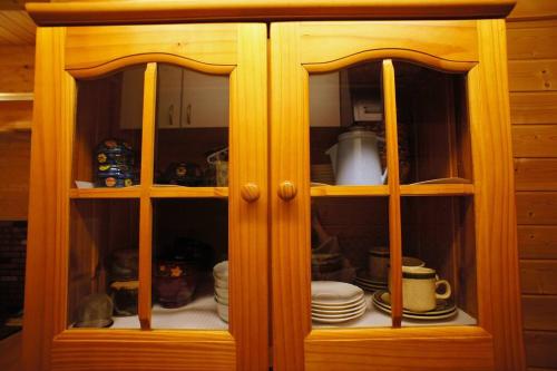 a wooden cabinet with plates and dishes in it at HARUNA CABIN 森の中のログハウス 、広々ウッドデッキでBBQ、公園散策、北軽井沢観光 in Tsumagoi