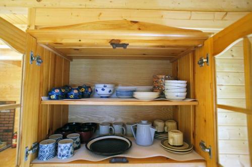 a wooden cabinet filled with dishes and bowls at HARUNA CABIN 森の中のログハウス 、広々ウッドデッキでBBQ、公園散策、北軽井沢観光 in Tsumagoi