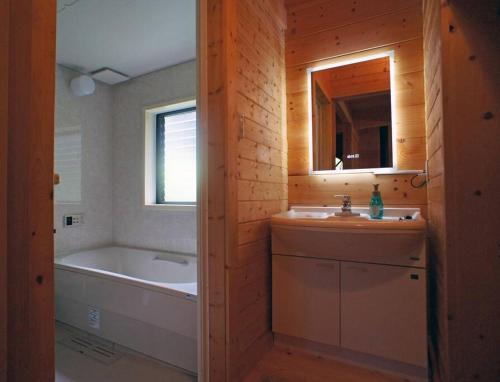 a bathroom with a tub and a sink and a bath tub at HARUNA CABIN 森の中のログハウス 、広々ウッドデッキでBBQ、公園散策、北軽井沢観光 in Azumaiokozan