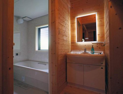 a bathroom with a tub and a sink and a bath tub at HARUNA CABIN 森の中のログハウス 、広々ウッドデッキでBBQ、公園散策、北軽井沢観光 in Tsumagoi