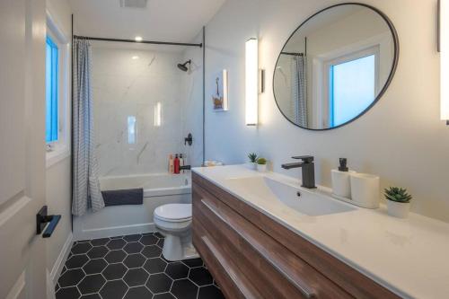 a bathroom with a sink and a toilet and a mirror at Kingsdale Designer Tiny House with Tesla Charger in Kitchener