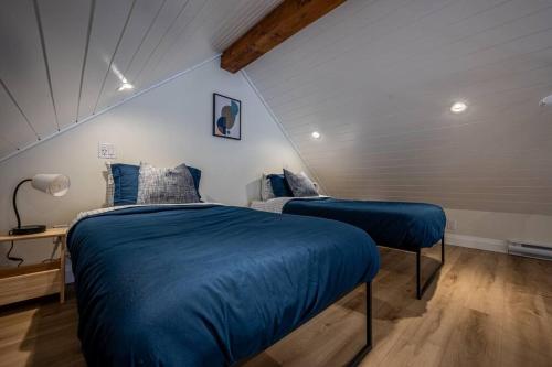 sypialnia z 2 łóżkami i niebieską kołdrą w obiekcie Kingsdale Designer Tiny House with Tesla Charger w mieście Kitchener