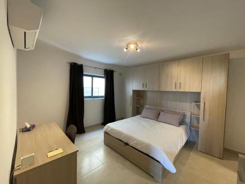 een slaapkamer met een bed en een tafel. bij Blue Skies Family Apartment with Terrace in St Paul's Bay