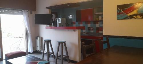 cocina con mesa y 2 taburetes en Departamento Céntrico en Villa Carlos Paz