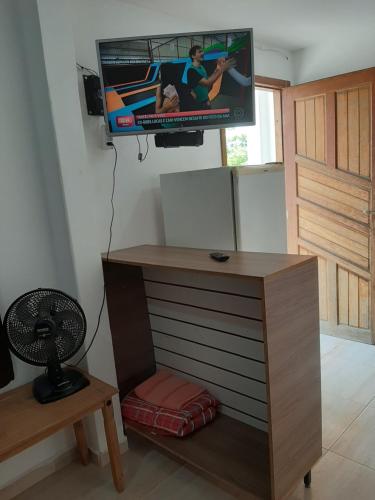 a room with a tv and a desk with a chair at Quarto em Matinhos PR in Matinhos