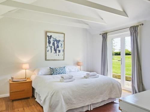 um quarto branco com uma cama grande e uma janela em The Stables em Birdham