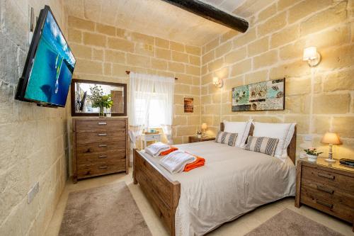 een slaapkamer met een groot bed en een flatscreen-tv bij Dar It-Torri Holiday Home in Kerċem