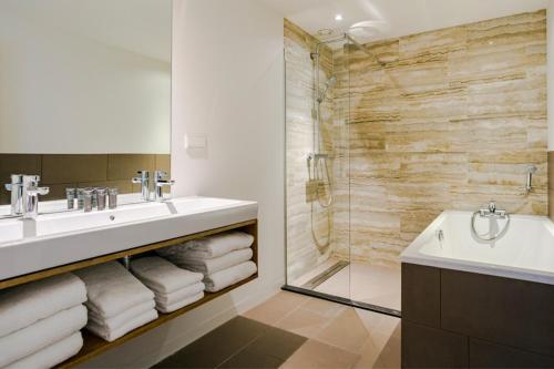een badkamer met een wastafel, een bad en een douche bij Bloemendaal Hotel Collection Apartments in Bloemendaal