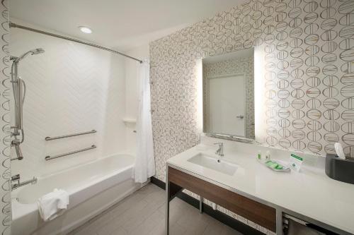 Holiday Inn & Suites Decatur-Forsyth, an IHG Hotel في ديكاتور: حمام مع حوض ومغسلة ومرآة
