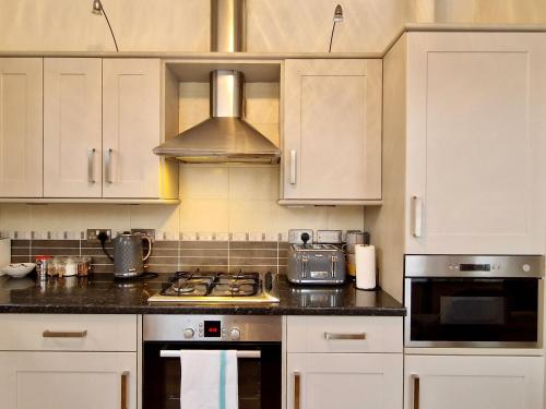a kitchen with white cabinets and a stove top oven at Spacious Luxury Serviced Apartment next to City Centre with Free Parking - Contractors & Relocators in Coventry