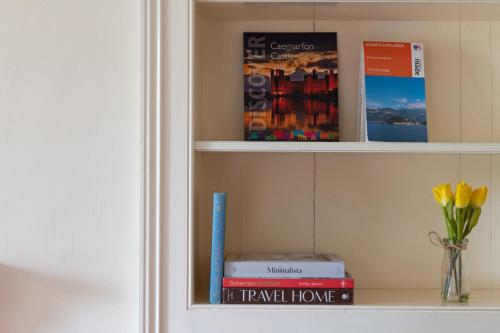 a book shelf with books and a vase of flowers at Finest Retreats - Bryn Seion in Llanrwst