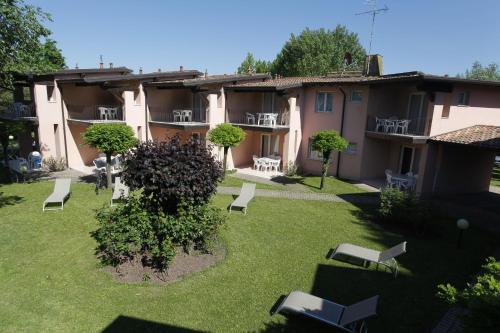 an apartment with a yard with chairs and trees at Villaggio Turistico Lugana Marina in Sirmione