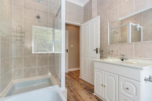 een badkamer met een bad, een wastafel en een douche bij Coney Glen Views in Knysna