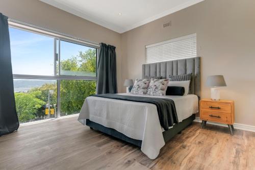 een slaapkamer met een bed en een groot raam bij Coney Glen Views in Knysna