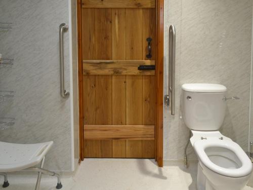 a bathroom with a toilet and a wooden door at Annexe Church Farm Barn in Stalham