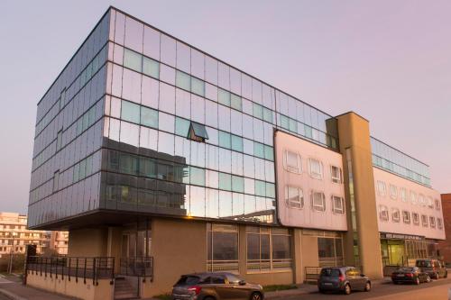 a large glass building with cars parked in front of it at Hôtel Les Gens De Mer Dunkerque by Popinns in Dunkerque