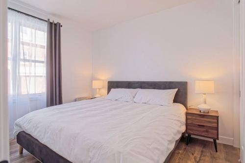 sypialnia z dużym białym łóżkiem i oknem w obiekcie 201 Condo au rez de chaussée , au coeur de Bromont w mieście Bromont