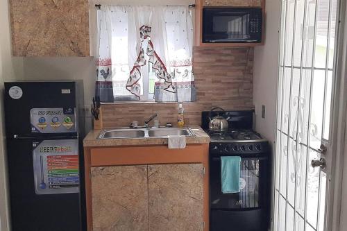 uma pequena cozinha com um lavatório e um fogão em Budget & Basic in Local Neighborhood, 7min Drive to Downtown Nassau Beach Paradise em Nassau