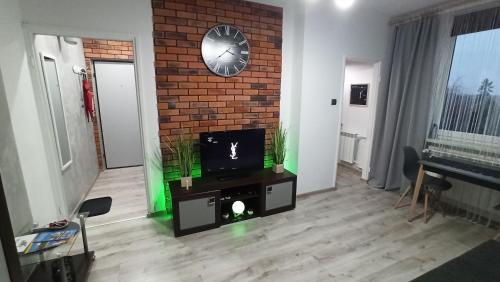 sala de estar con TV y pared de ladrillo en Apartament w Sandomierzu przy Starówce, en Sandomierz
