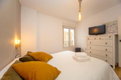 1 dormitorio con 1 cama blanca y TV en la pared en Rincón de Bruno y Duque, en Cenes de la Vega
