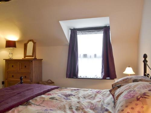 a bedroom with a bed and a window at Rose Cottage in Taxal