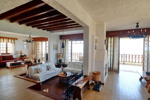 una gran sala de estar con sofás, mesas y ventanas. en Antorina Grande beachfront house, en Kamárion