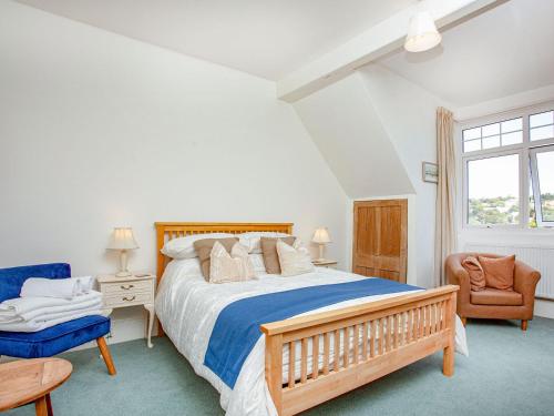 a bedroom with a large bed and a chair at The Coach House At Vane Hill in Torquay