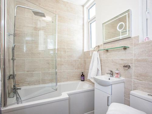 a bathroom with a shower tub and a sink at The Coach House At Vane Hill in Torquay