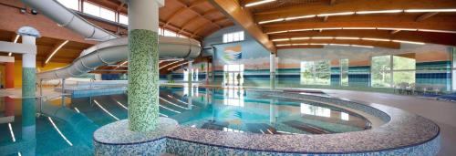 a large swimming pool with a slide in a building at Apartmán Wellness hotel Frymburk in Frymburk