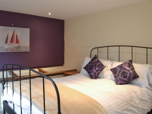 a bedroom with a large bed with purple pillows at Meadow Barn in Ellingham