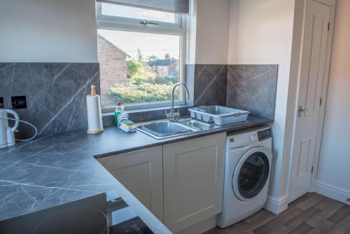 a kitchen with a sink and a washing machine at Toothbrush Apartments - Ipswich East - Cauldwell Ave in Ipswich