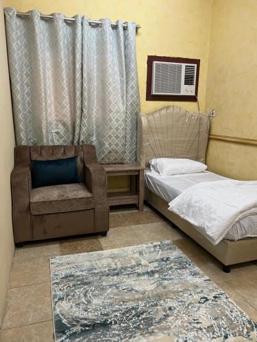 a bedroom with two beds and a chair and a rug at سويتات مفروشة in Al Hofuf
