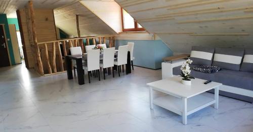 ein Wohnzimmer mit einem Tisch und weißen Stühlen in der Unterkunft Gościniec u Zalesia Warchały Noclegi Zalewski in Warchały
