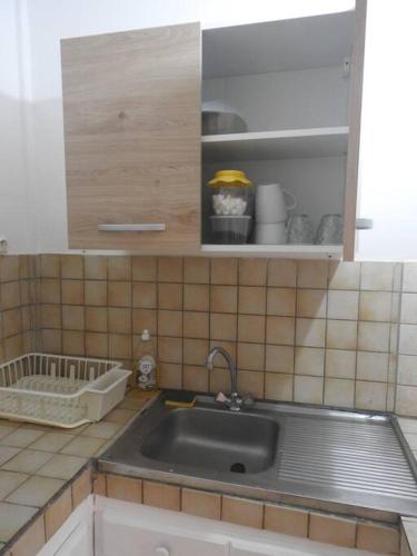 eine Küche mit einem Waschbecken und einer gefliesten Wand in der Unterkunft STUDIO HIBISCUS-CH Vue sur mer,Plage,Clim in Les Anses-dʼArlets