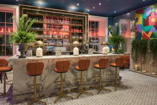 a bar with orange bar stools in a room at Tigerlily in Edinburgh