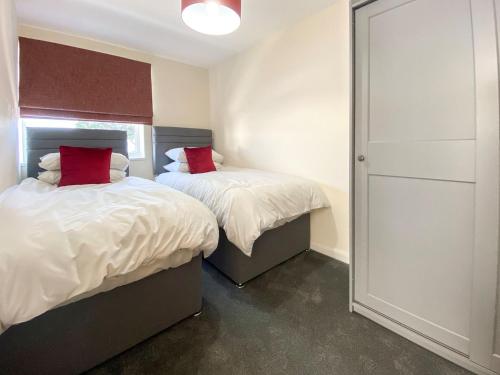 a bedroom with two beds with red pillows on them at Uk40237 - Beach Bank Bungalow in Lympne