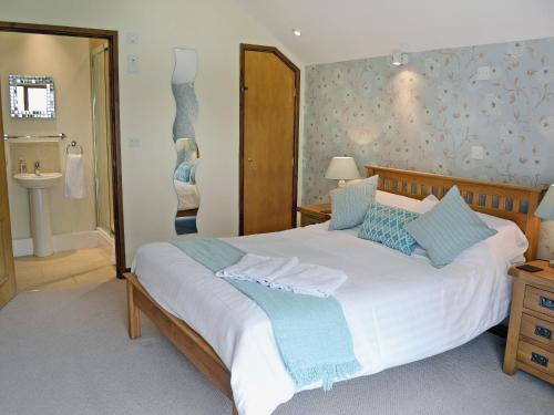 a bedroom with a large white bed with blue pillows at Black Thorn Cottage in Falmouth