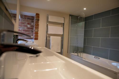 a bathroom with a white tub and a sink at Rollestone Coach House in Shrewton