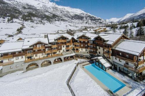 a resort with a swimming pool in the snow at Pour 4 pers résidence 4* au pied des pistes in Lanslebourg-Mont-Cenis