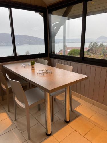 une table et des chaises dans une pièce avec des fenêtres dans l'établissement Maisonnette vue panoramique lac d'Annecy, à Veyrier-du-Lac