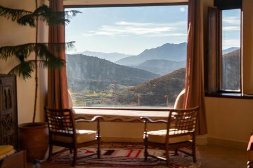 a room with two chairs and a large window at Touda Ecolodge Atlas Mountains in Zawyat Oulmzi